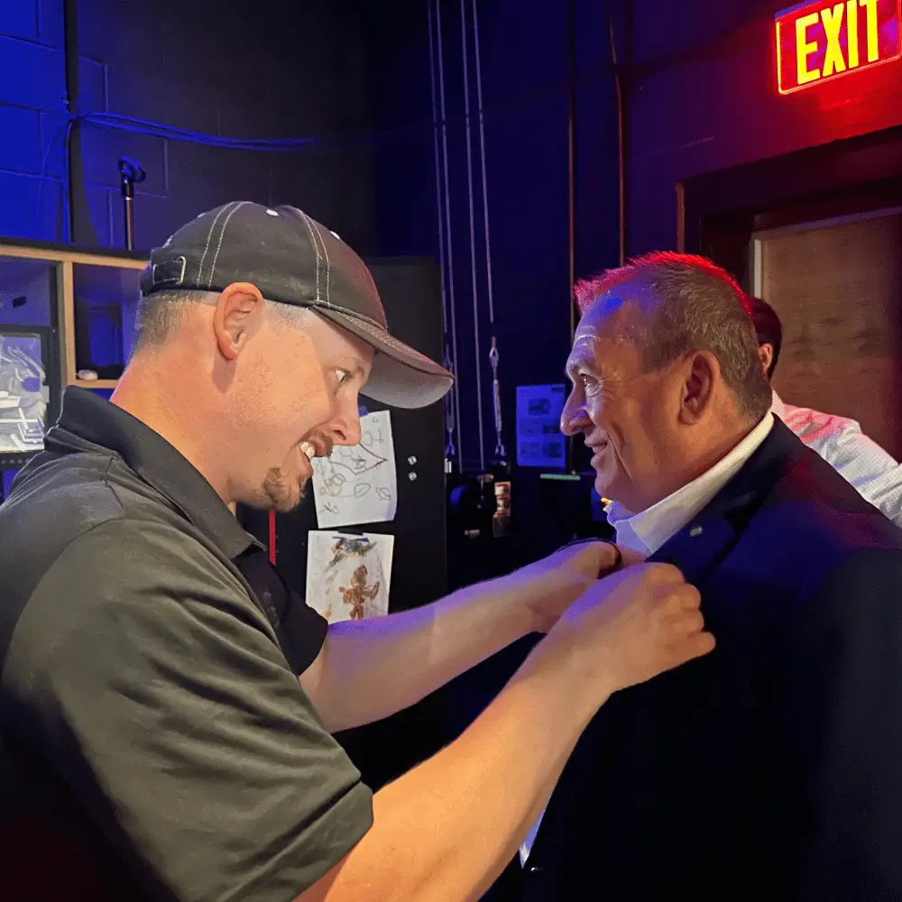 Carl Moellenberg backstage as a crew member pins a microphone to his jacket