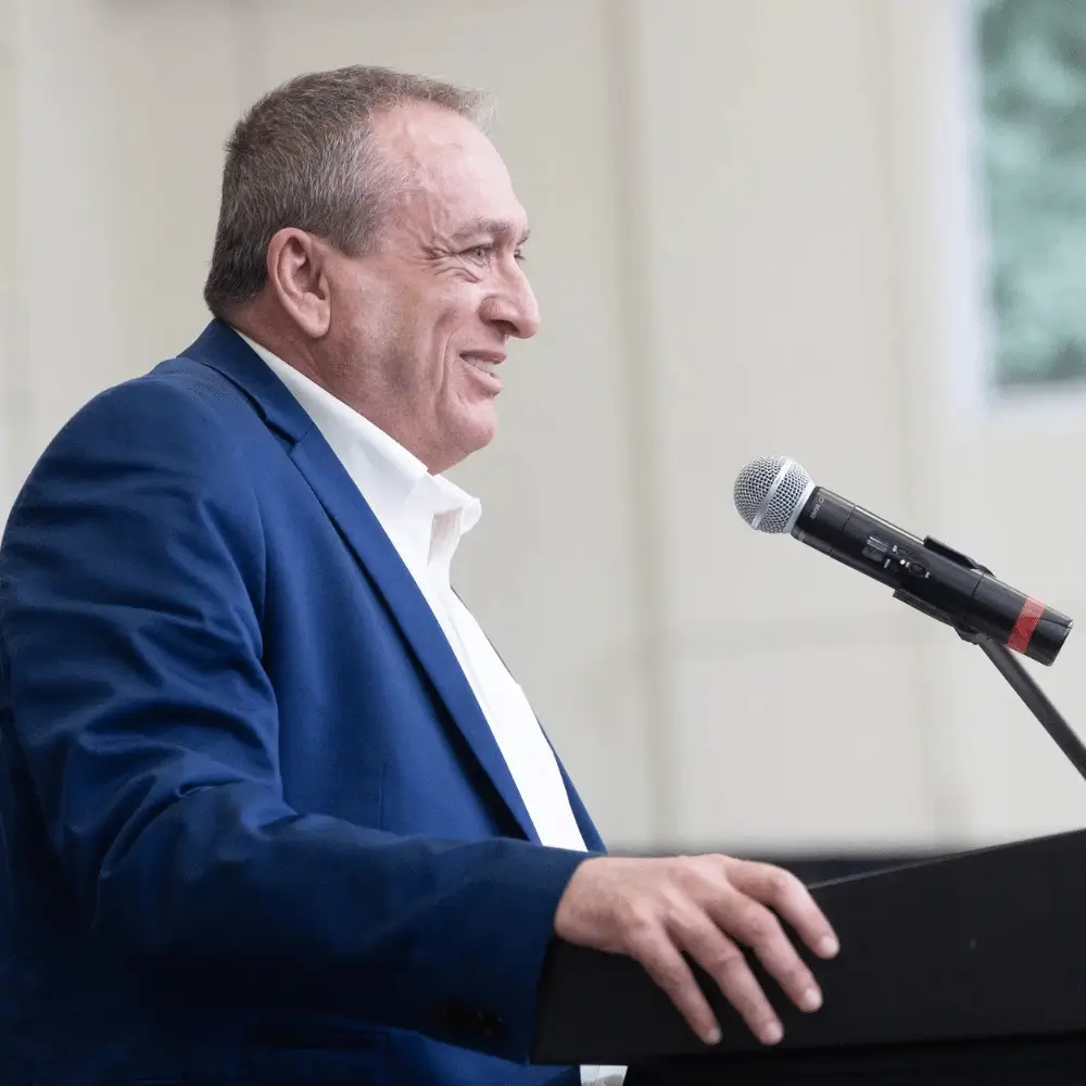 Carl Moellenberg smiling as he speaks at a podium microphone