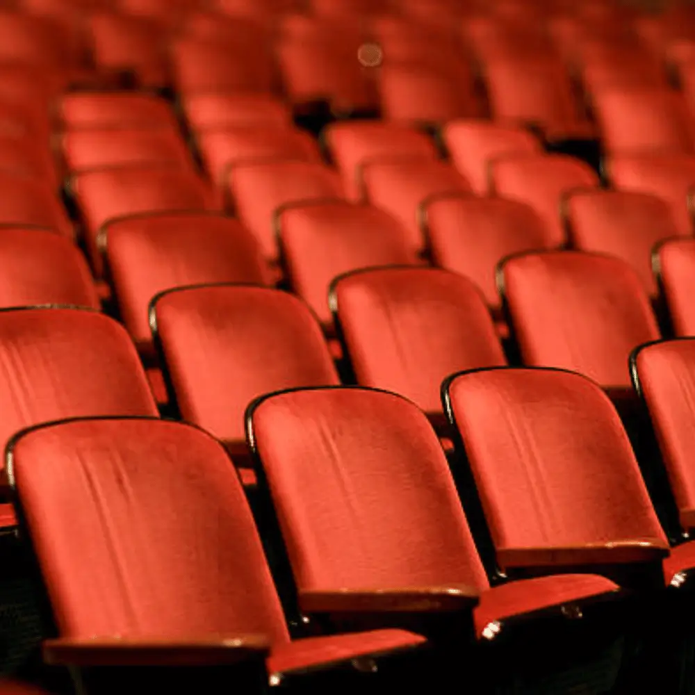Rows of empty red velvet theater seats before a performance