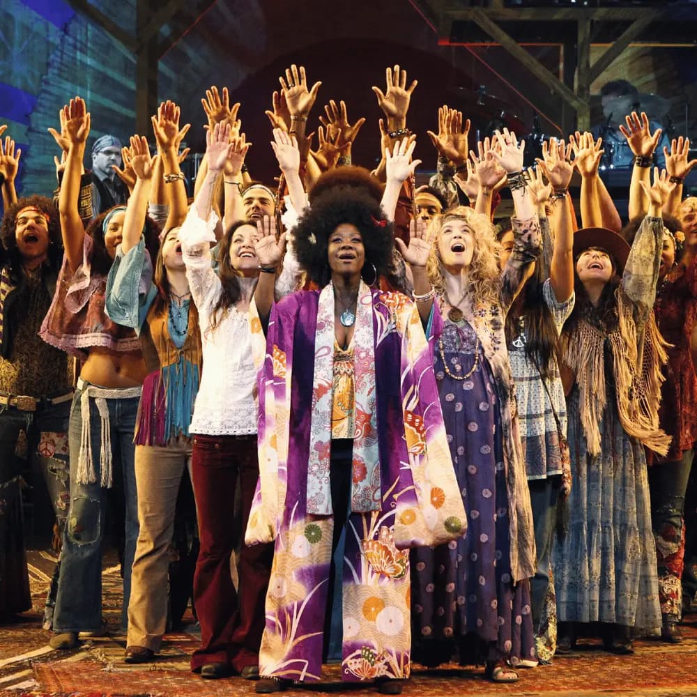 The cast of a Broadway musical raising their hands in a joyful curtain call
