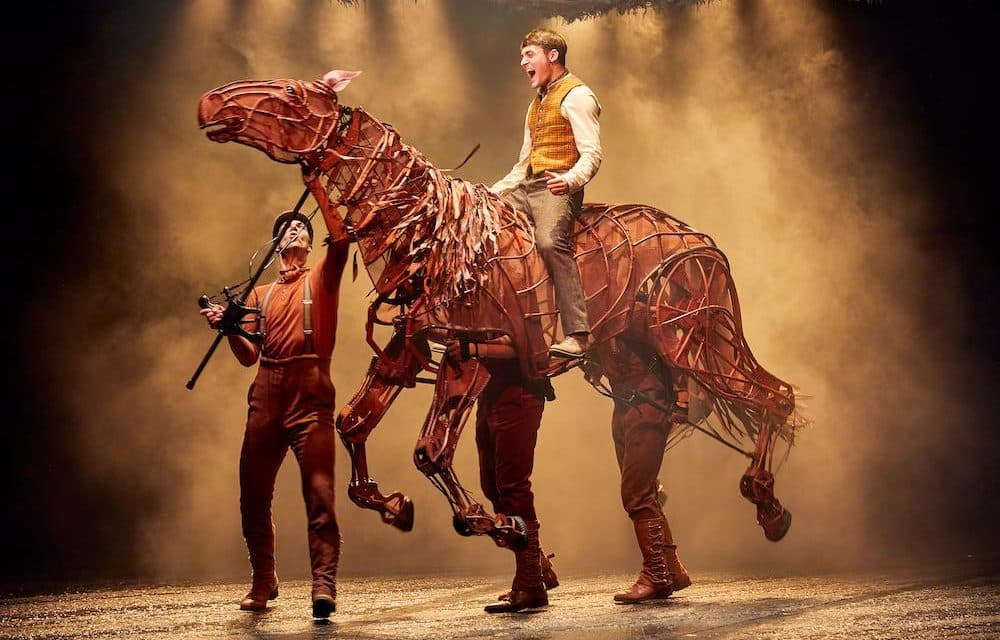 An actor riding the life-size Joey horse puppet from War Horse on a smoke-lit stage